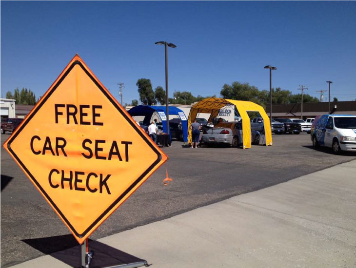 Yellow diamond sign displays "FREE CAR SEAT CHECK" text.