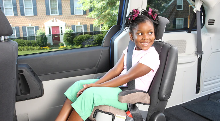Young girl seated safely in a car booster seat